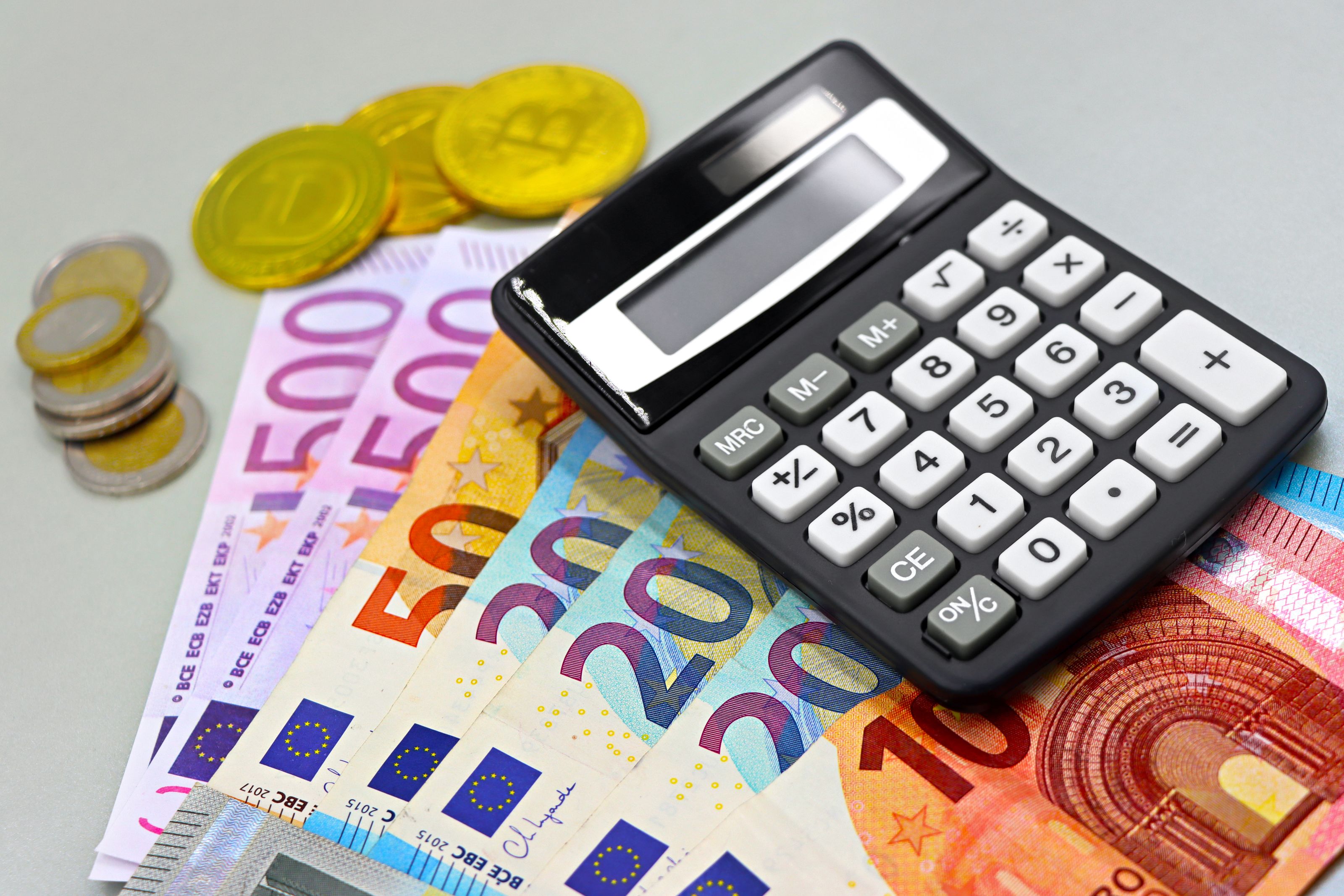 Image of euro banknotes, coins, and a calculator for financial planning. Perfect for finance themes.
