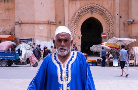 Elderly man in traditional attire at Fès medina entrance showcasing Moroccan culture.