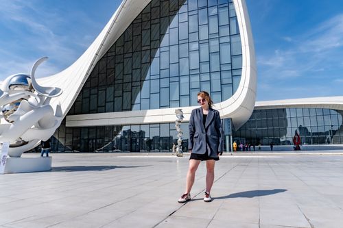 Free Woman standing in front of unique modern architectural landmark on a sunny day. Stock Photo