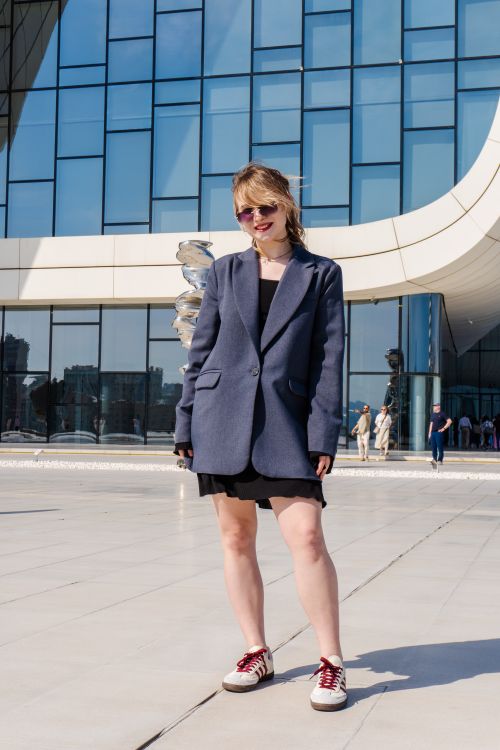 Free Stylish woman in sunglasses standing by modern glass building. Urban fashion setting. Stock Photo