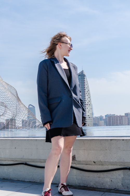 Free Stylish woman in blazer enjoying sunny day on rooftop with city skyline view. Stock Photo