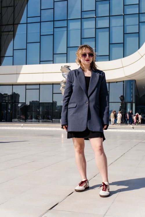 Free Fashionable woman wearing sunglasses and an oversized blazer outdoors in daylight. Stock Photo