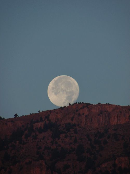Free A stunning full moon rising over a rugged mountain ridge during twilight. Stock Photo