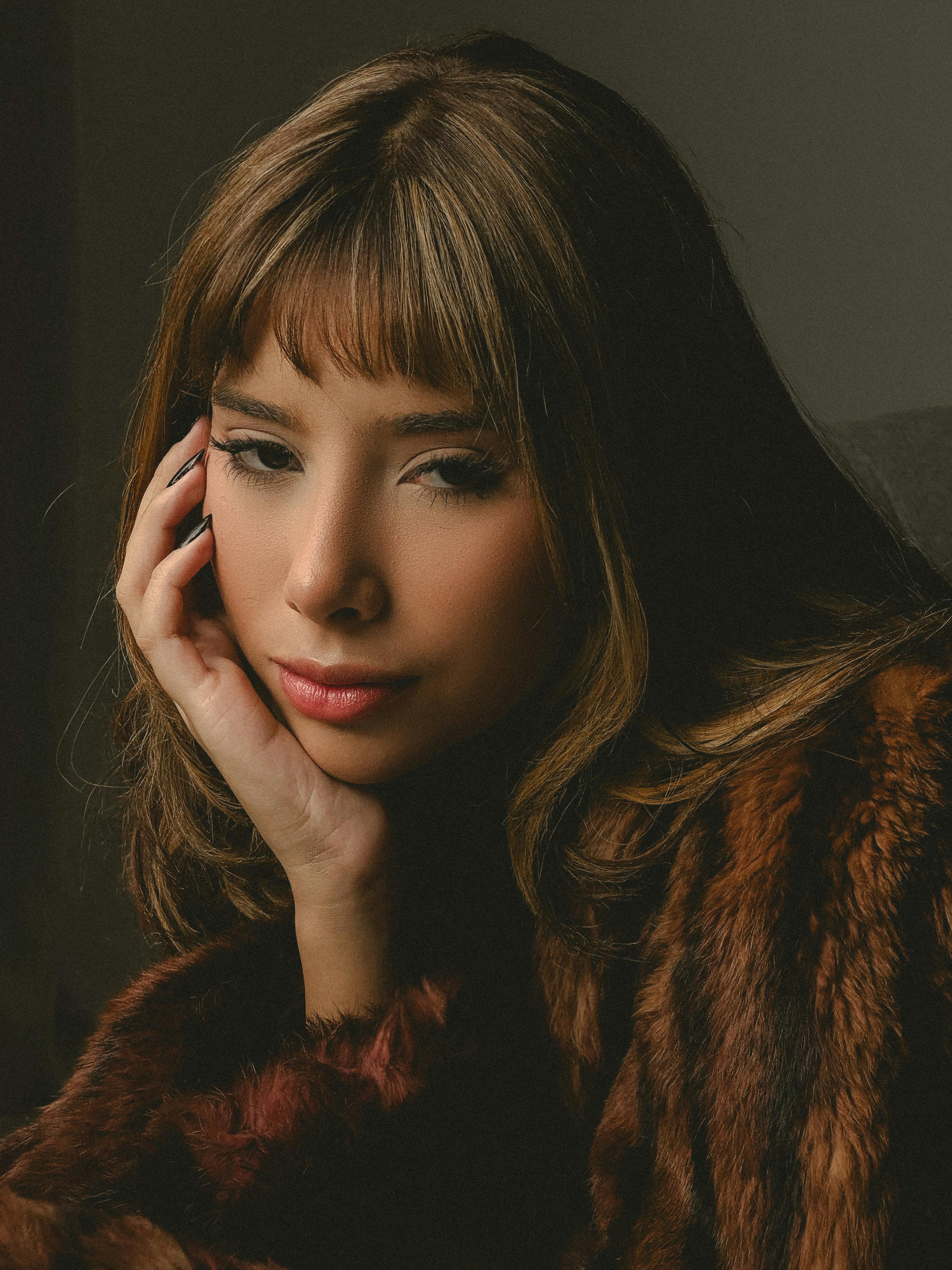 Close-up portrait of a young woman in fur coat, deep in thought indoors, Brazil.