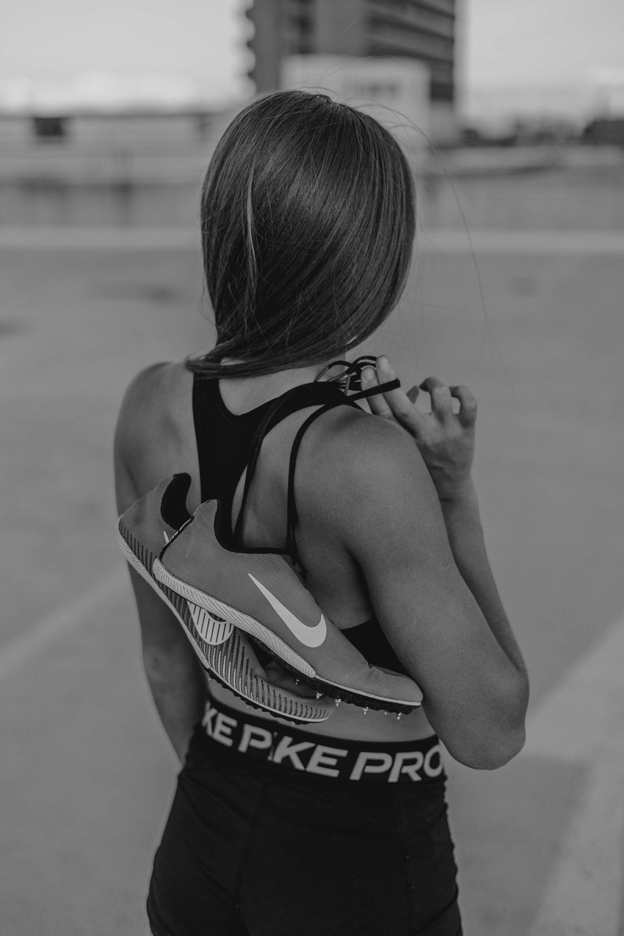 Black and white portrait of an athlete holding shoes, capturing fitness and style in Johannesburg.