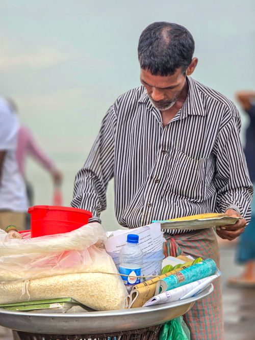 Free Street vendor in Bangladesh selling goods on a sunny day, displaying traditional items and interacting with customers. Stock Photo
