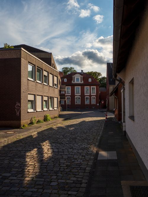 Free A picturesque alleyway with brick buildings and a cobblestone path under a clear sky. Stock Photo