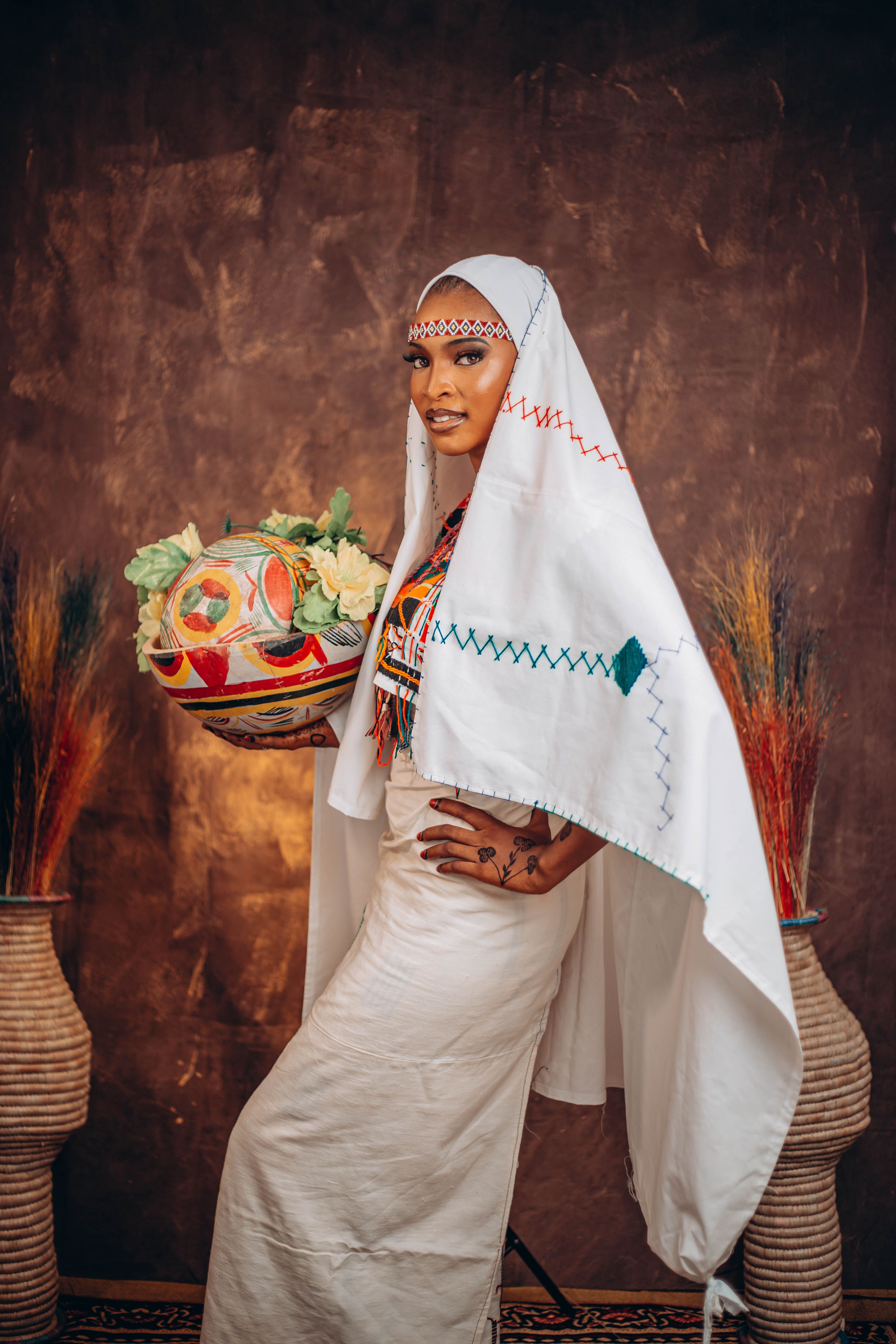 A woman in traditional African attire holding a colorful basket, symbolizing cultural heritage.