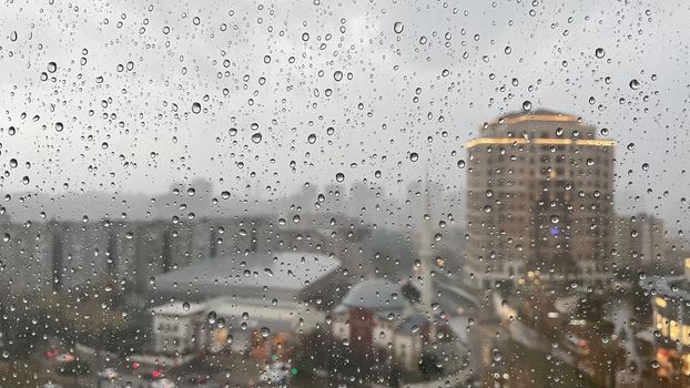 View of Istanbul cityscape through rain-soaked window, capturing urban life under overcast sky.