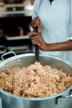 Chef stirs a pot of freshly cooked rice in a professional kitchen setting.
