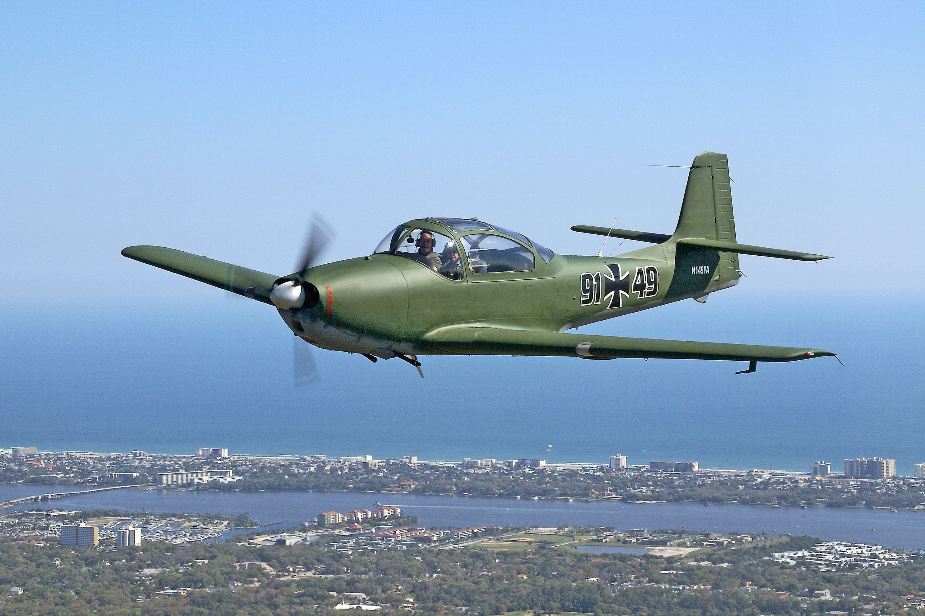 A vintage Focke-Wulf aircraft flying over the scenic Florida coastline on a clear day.