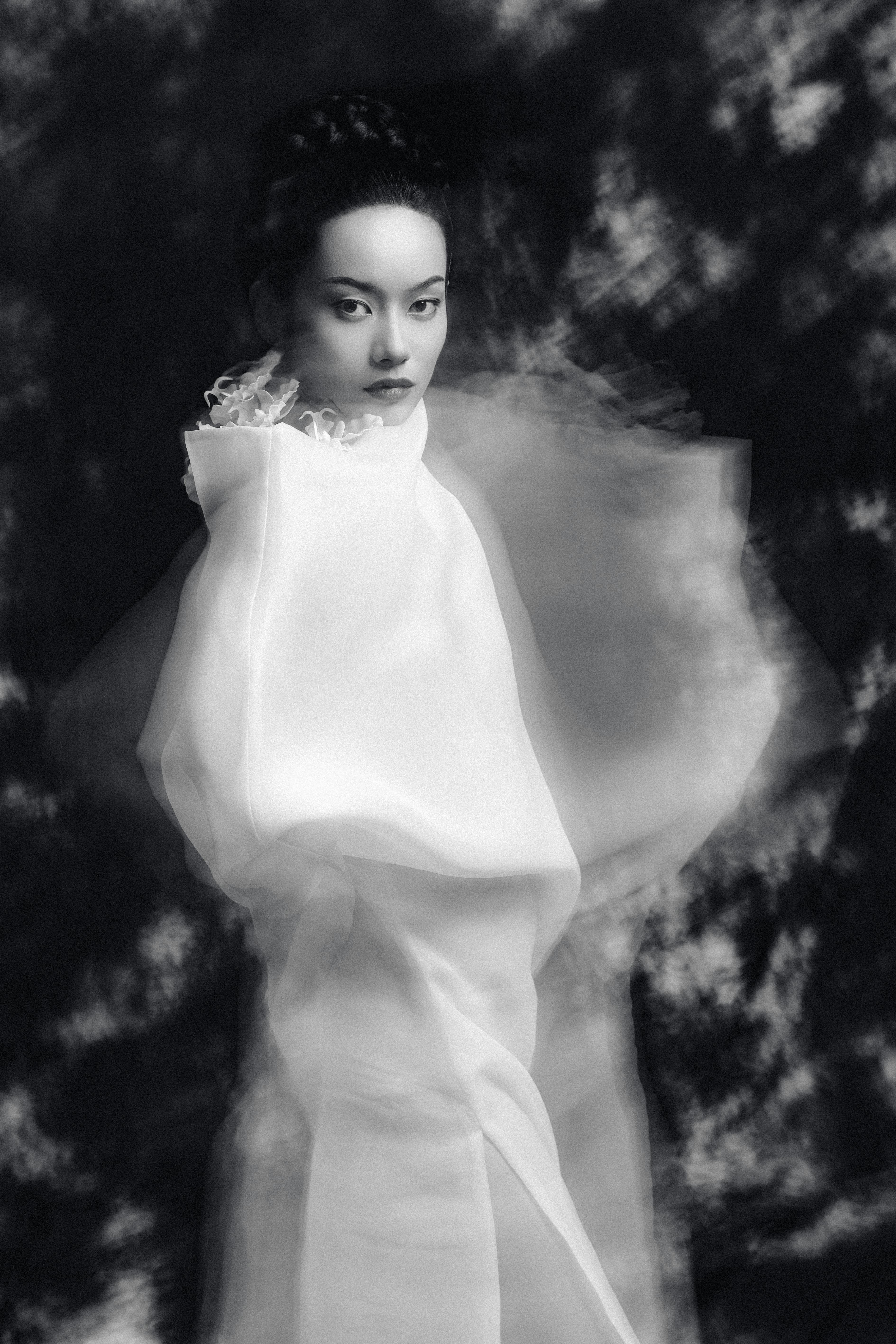 Ethereal black and white portrait of woman in elegant attire.