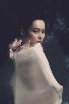 A serene and artistic portrait of a woman with floral design on fabric, exuding elegance.