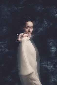 A dreamy and ethereal portrait of a woman in soft focus with a floral accent.