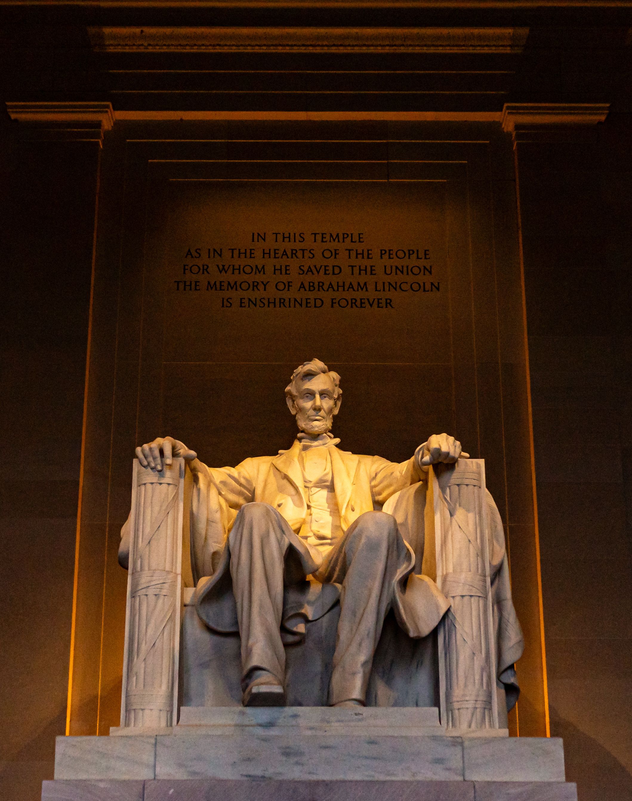 View of the iconic Abraham Lincoln statue inside the Lincoln Memorial, illuminated beautifully indoors.