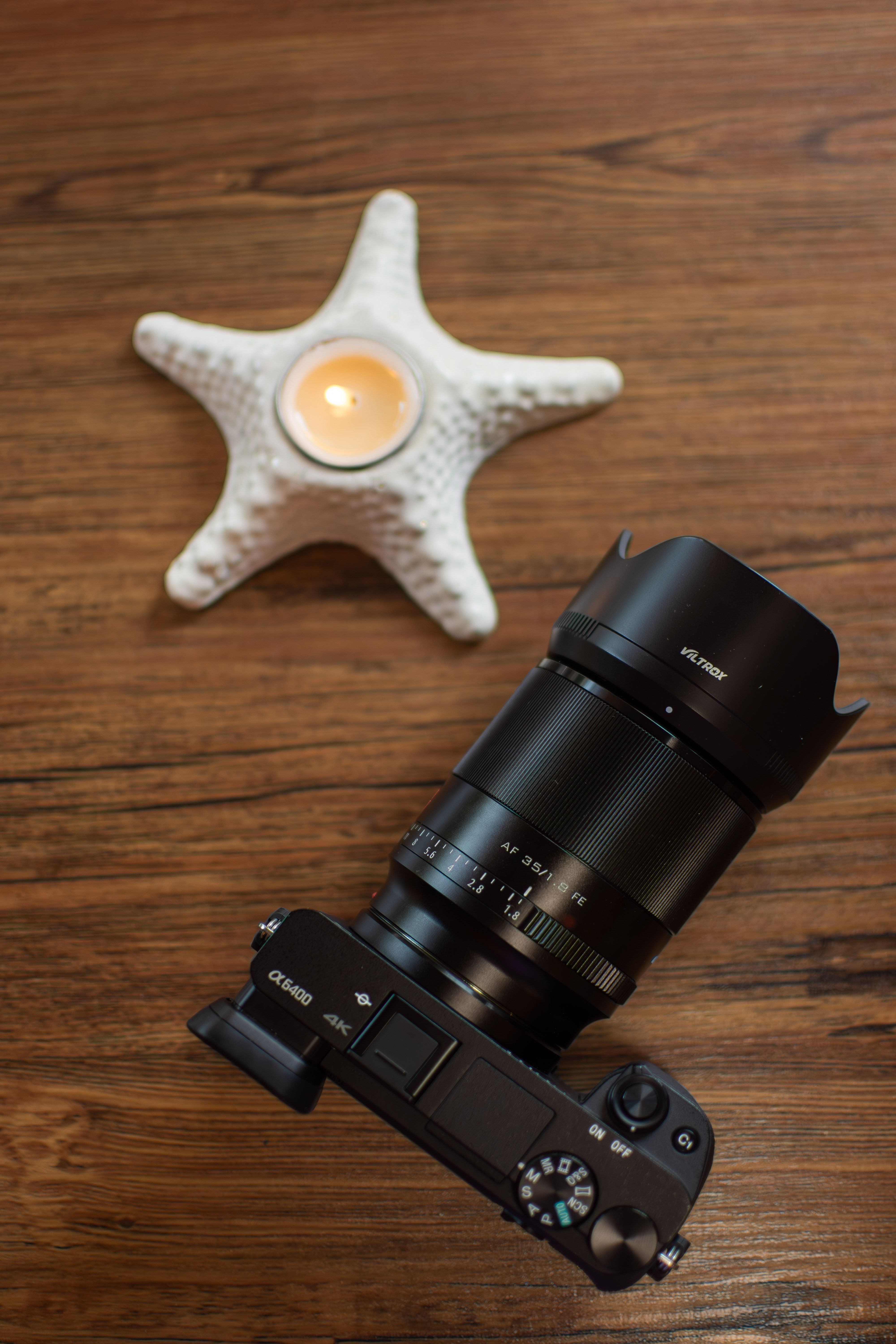 Un portacandele a forma di stella marina e una fotocamera su un tavolo di legno, creando una composizione accogliente e artistica.