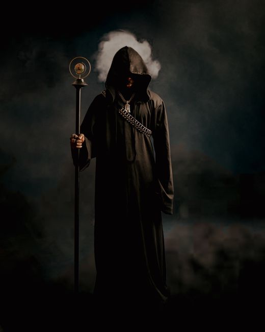 A hooded figure holding a staff creates a mysterious and mystical atmosphere.