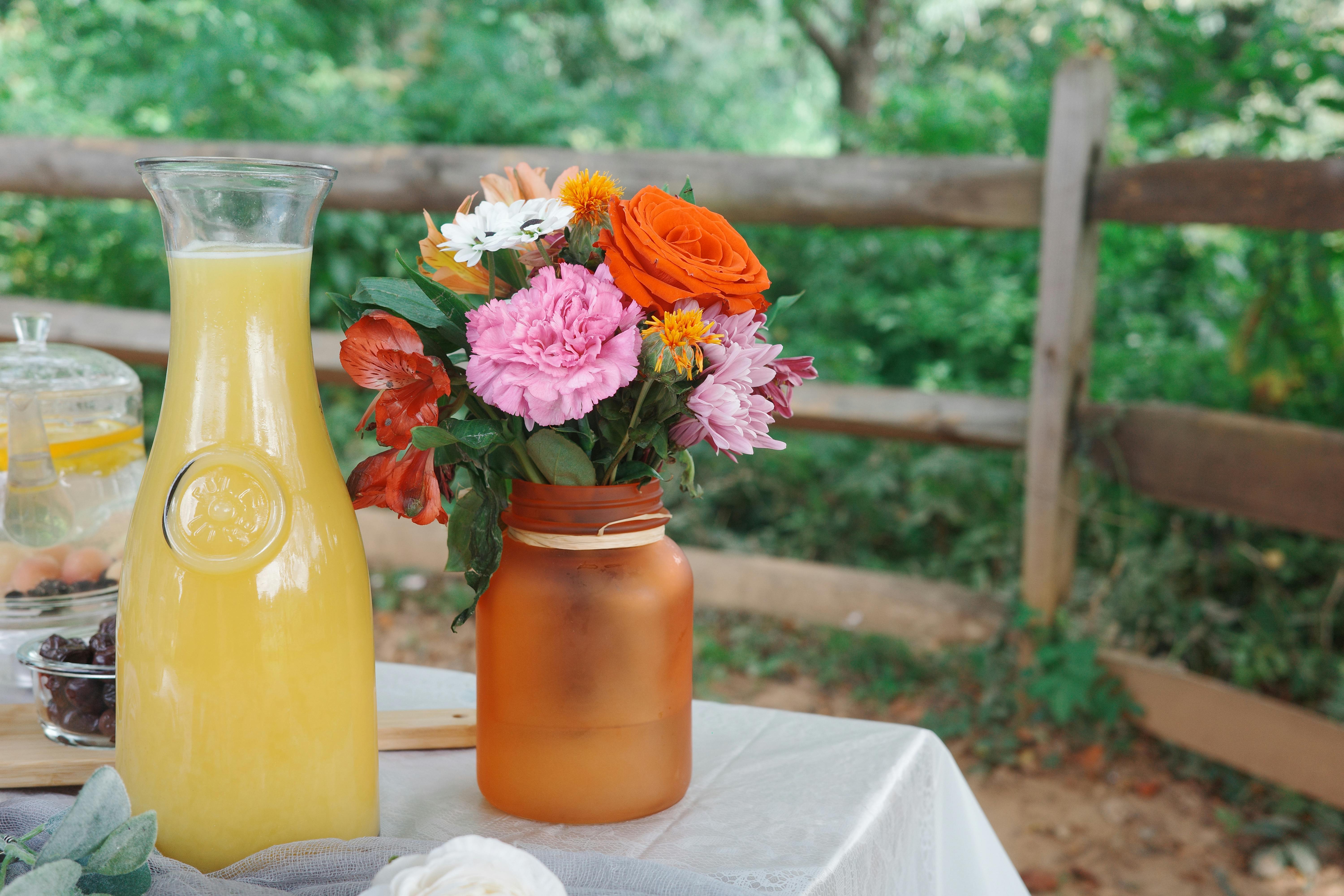 Colorful flowers in vase with lemonade outdoors.
