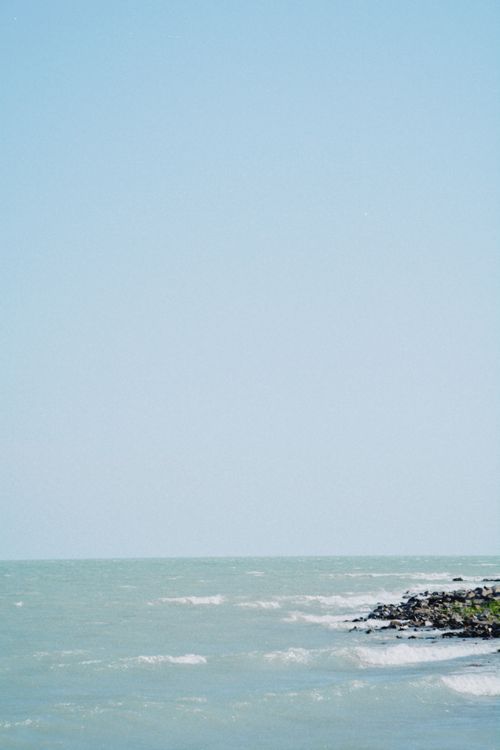 Free Peaceful scene of Lake Balkhash's shoreline with gentle waves against the rocks under a clear sky. Stock Photo