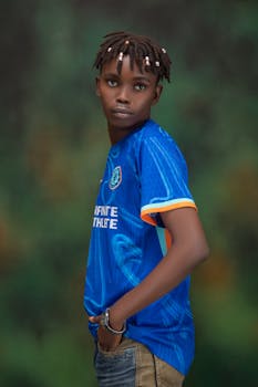 Stylish young man in a blue athletic jersey posing confidently indoors.