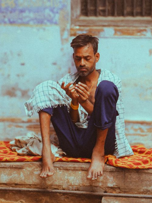 Free A contemplative man sits cross-legged on a step, focused and serene, with traditional attire and rustic background. Stock Photo