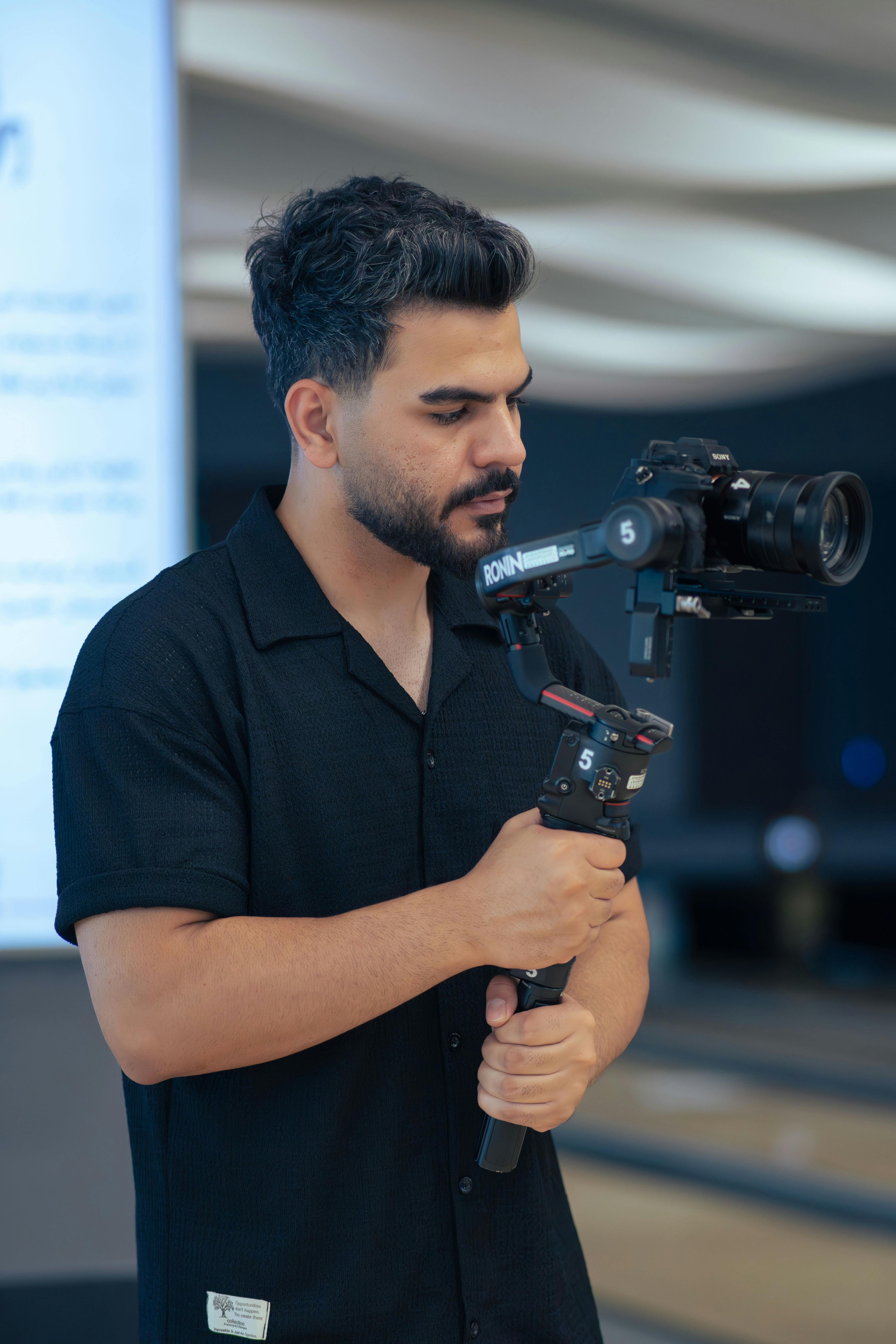 A male videographer with a gimbal working indoors, captured in Tehran, Iran.