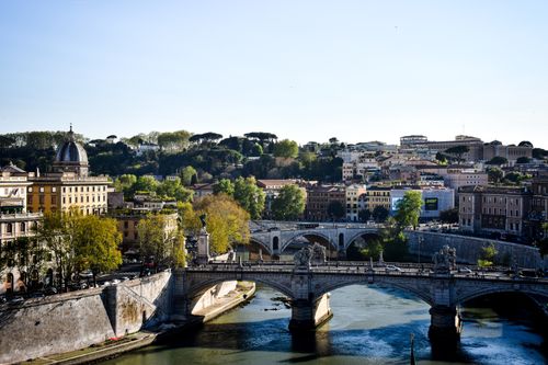 Beautiful view of Ponte Sant'Angelo spanning the Tiber River in Rome, Italy under a clear sky.