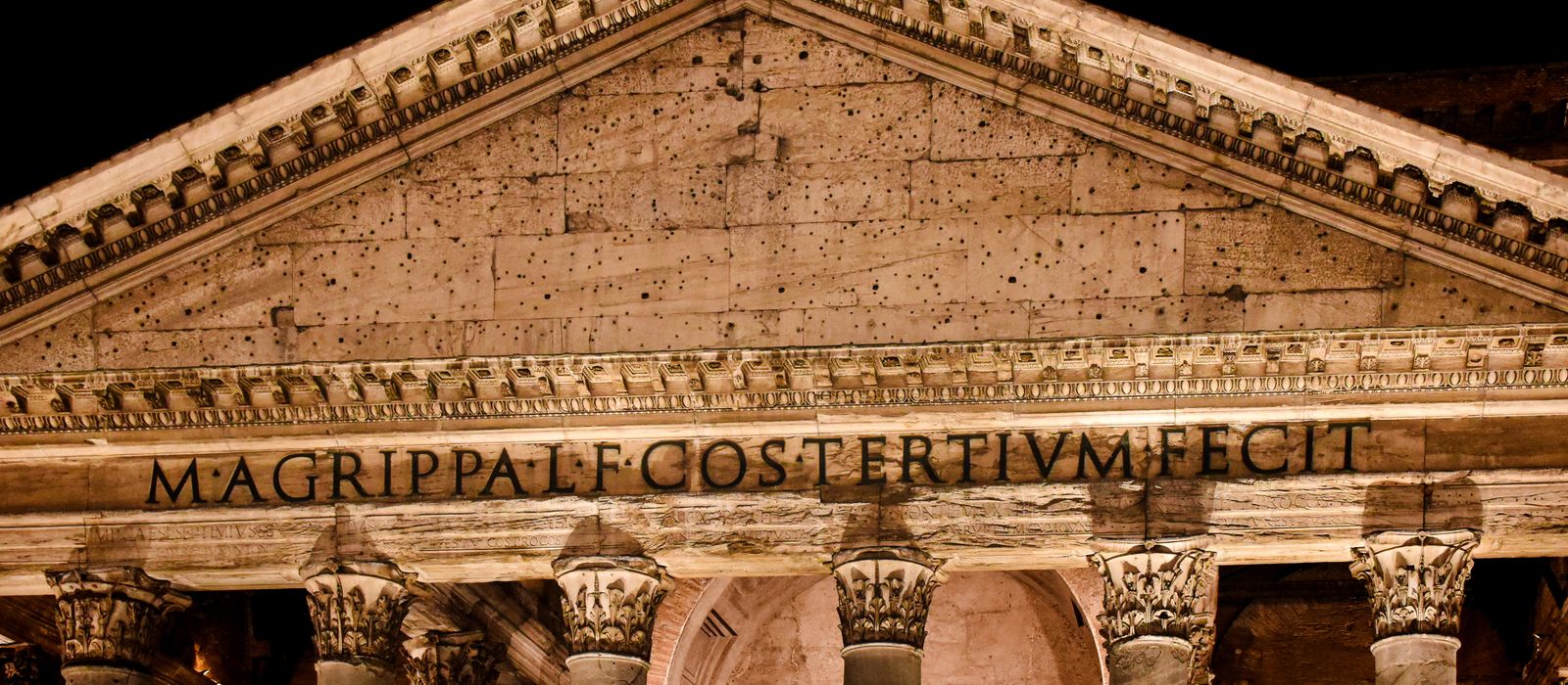 Night view of the Pantheon in Rome, featuring ancient Roman architecture and Latin inscription.