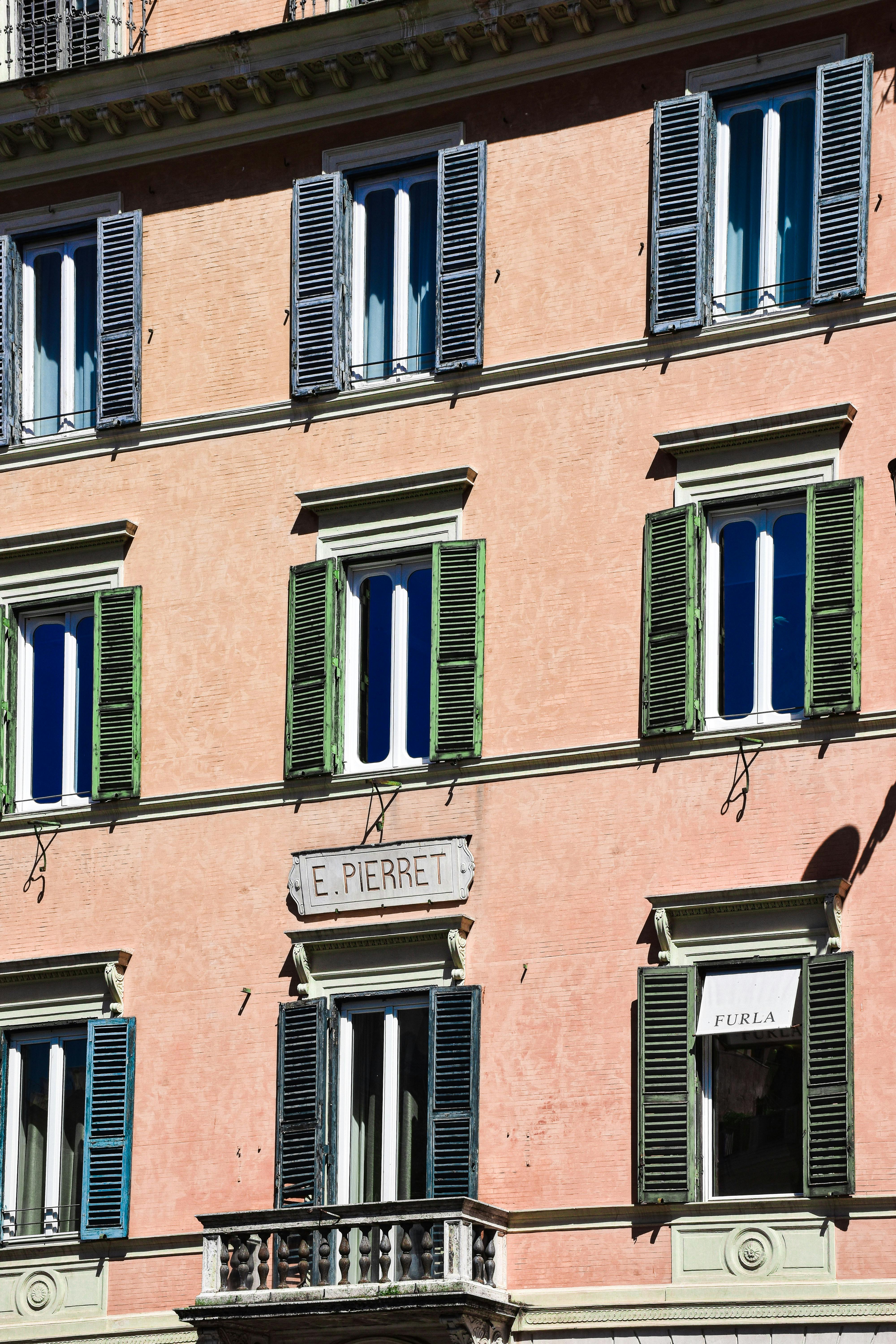 Colorful facade of a historic building with shutters in Rome's Lazio region.
