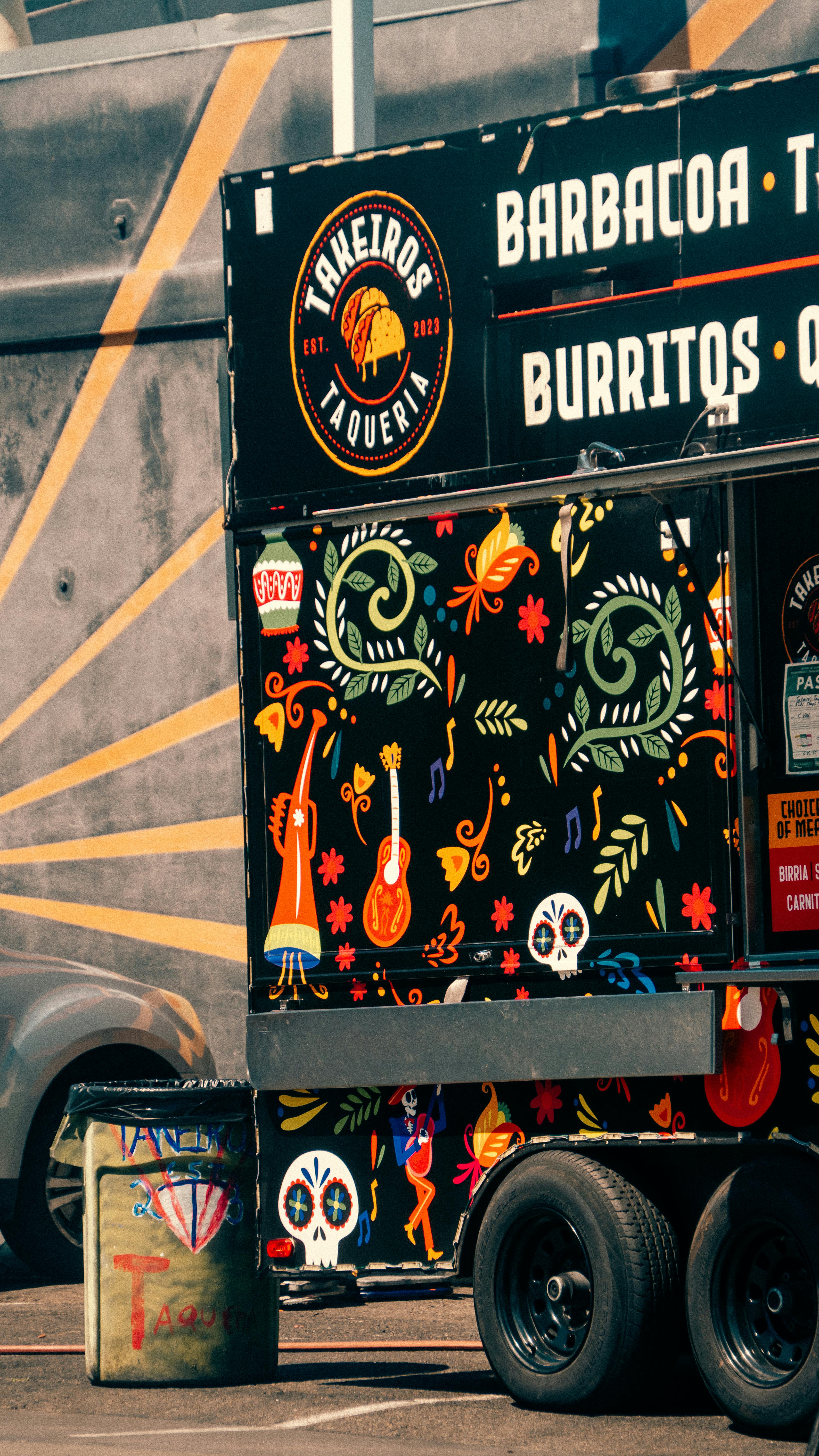 Colorful Mexican food truck with vibrant artwork and bold textures in a sunny urban setting.