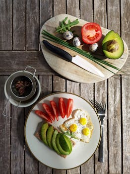 Delicious healthy breakfast featuring avocado, quail eggs, and tomatoes on rustic table.