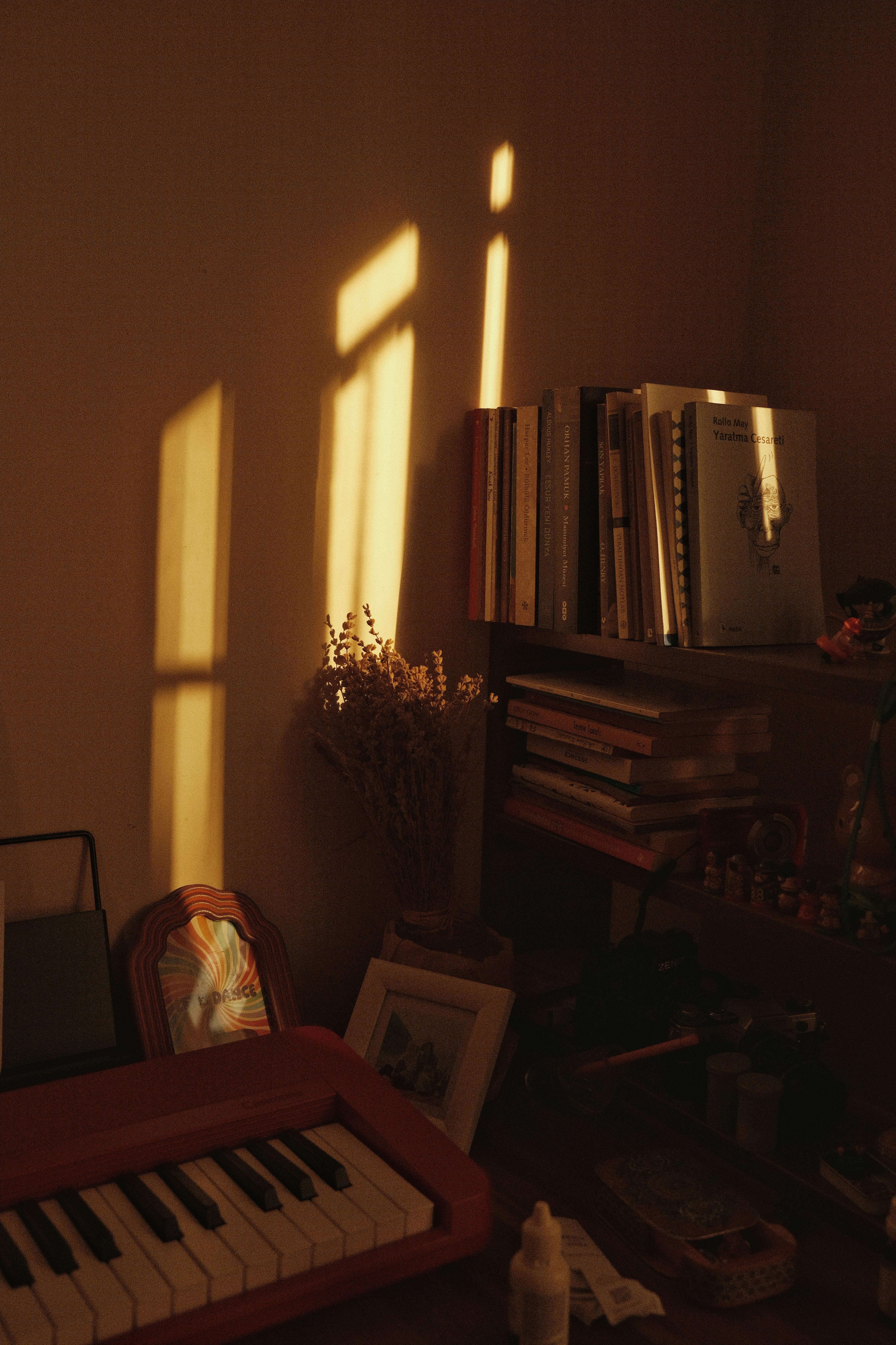 Warm light illuminating a cozy room with books, a keyboard, and aesthetic shadows.