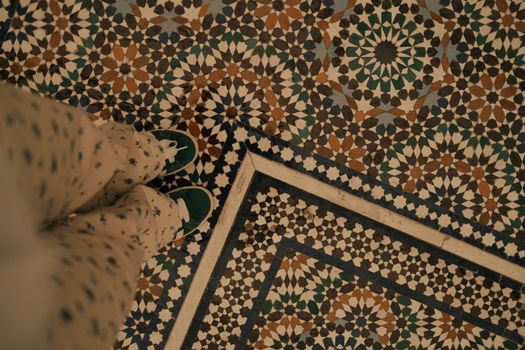 Colorful Moroccan tile pattern with a person's legs and shoes, captured in Paris.