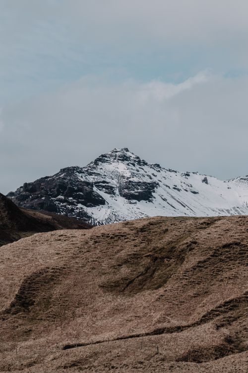 Free A serene view of a snow-capped mountain against a moody sky, capturing nature's beauty. Stock Photo