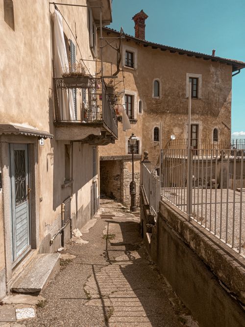 Free Charming Italian alleyway with rustic buildings and historical architecture under a clear sky. Stock Photo