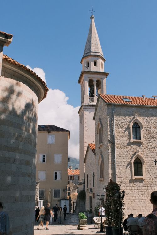 Free Charming medieval church with bell tower and people in a sunny European town square. Stock Photo