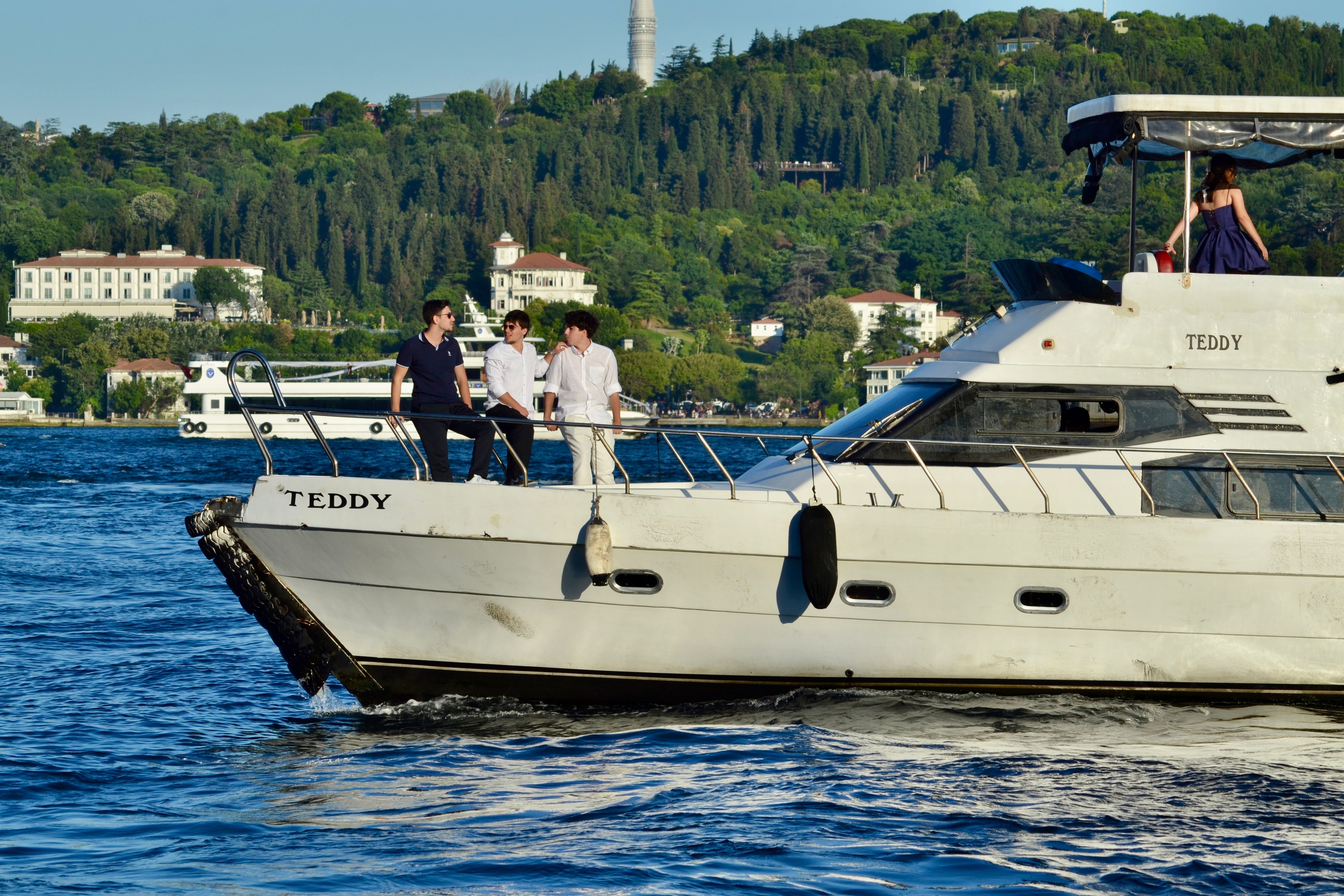Luxury yacht with people enjoying a scenic ride along lush green coastal landscape.