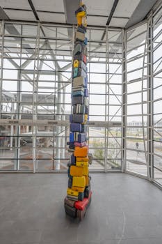 A stack of colorful suitcases forming a tall sculpture in Santiago airport's modern atrium.