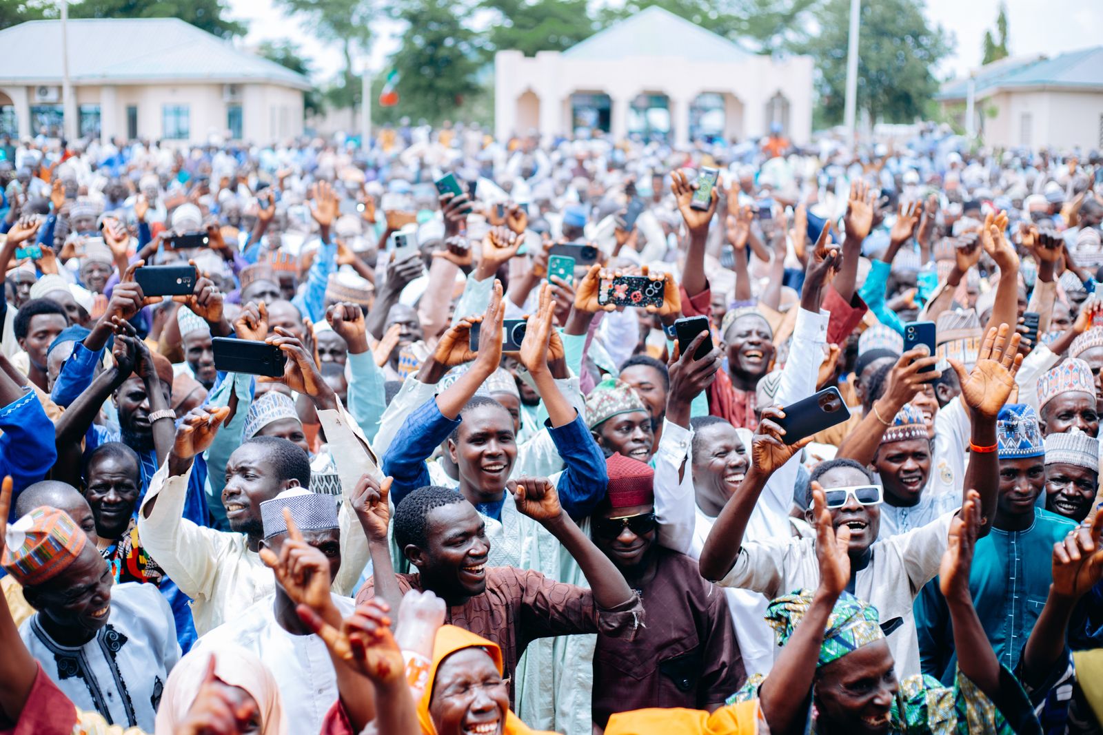 A large community gathering outdoors with raised hands — photo by Moh DIKKO Photography on Pexels