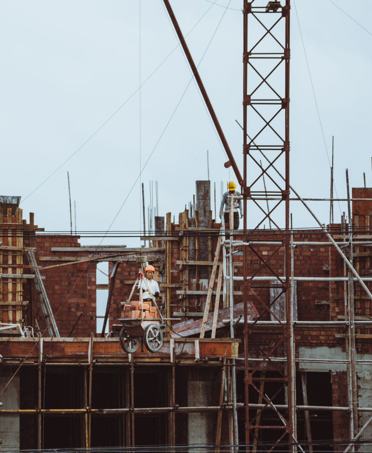 Ouvrier sur un échafaudage, grues de chantier en arrière-plan – Bureau d'études au Burundi