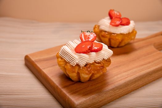 Appetizing strawberry tarts with cream cheese on a wooden board, perfect for dessert.