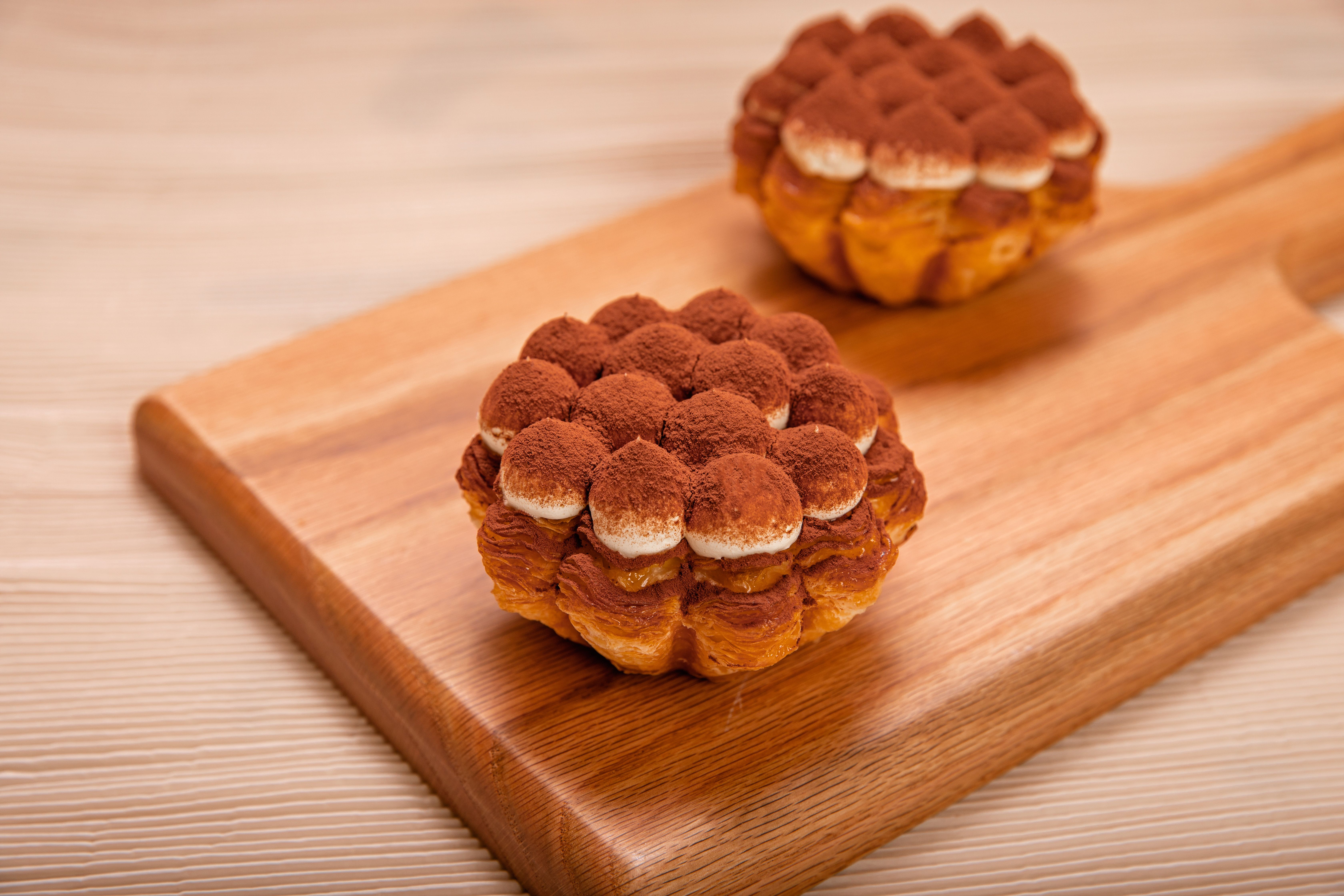 Two chocolate cream desserts with cocoa powder on a wooden board. Perfect for sweet treats or bakery displays.