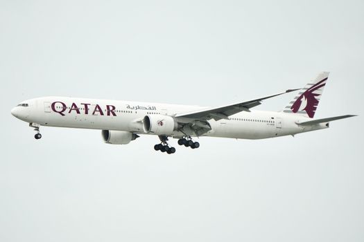 Qatar Airways Boeing 777 aircraft captured mid-flight against a clear sky.