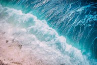 航拍镜头中，碧绿的海浪生动地拍打着海岸，展现了大自然的原始之美