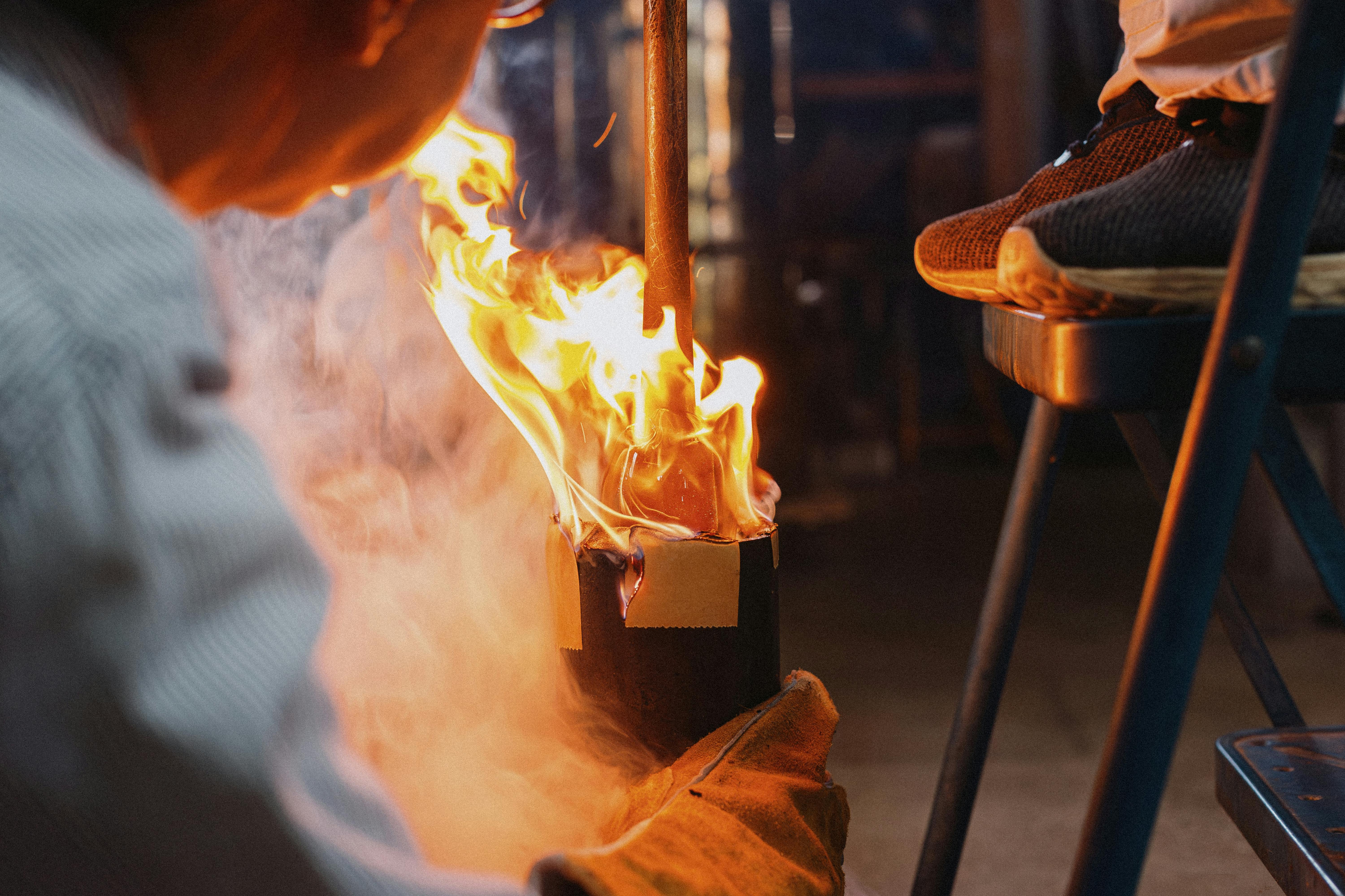 Artisan glass blowing process with flames and tools in Nagano, Japan workshop.