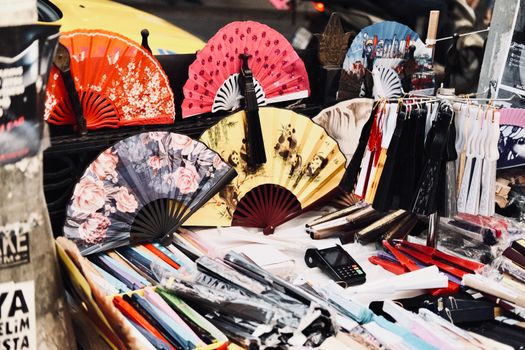 Vivid display of traditional hand fans at an outdoor market stall, showcasing diverse designs and colors.