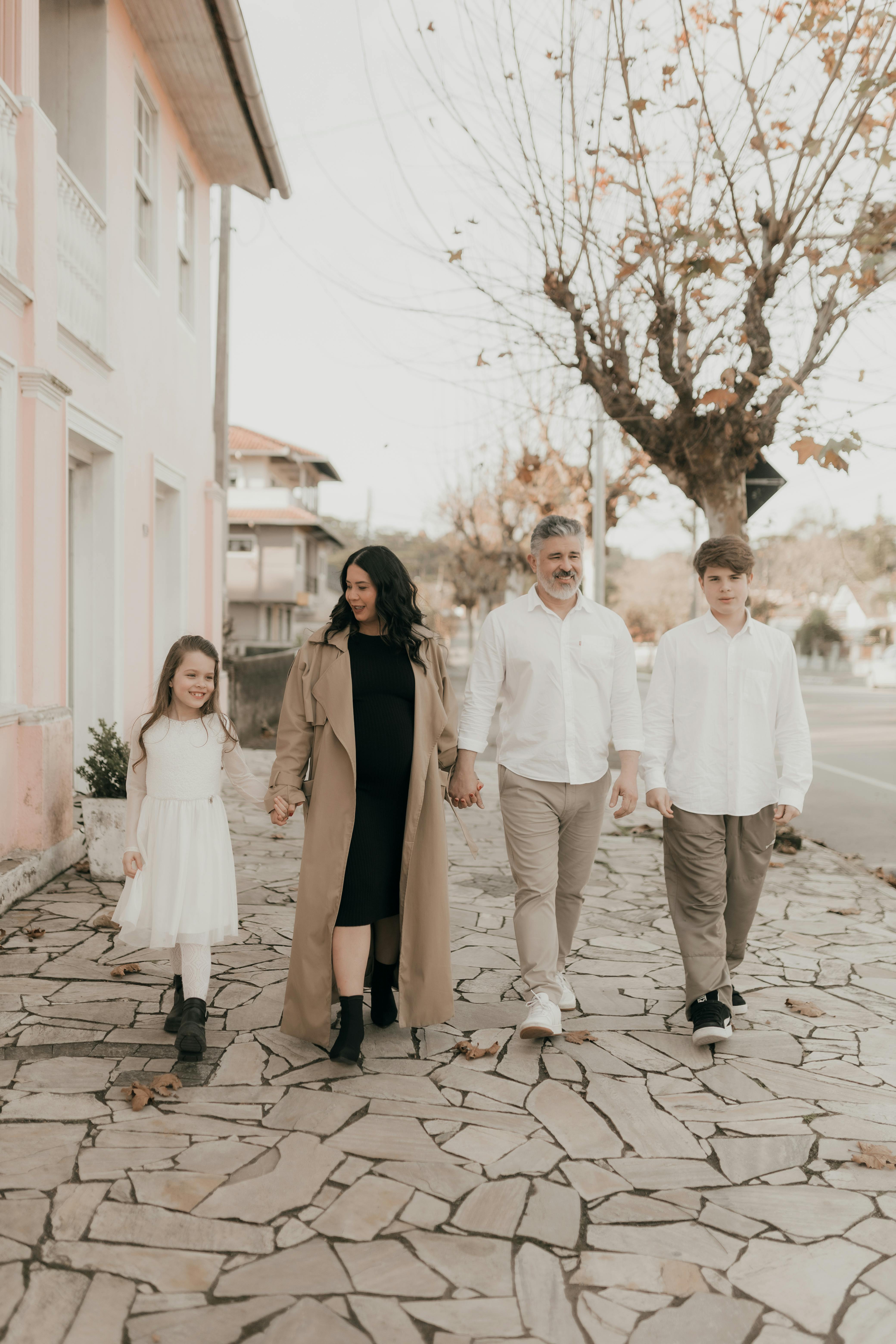 Family of four walking on a scenic autumn street holding hands.