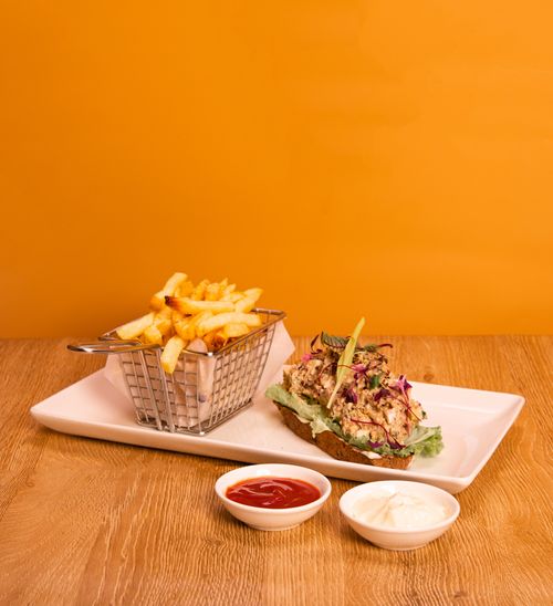 Free Tasty open sandwich with fries and sauces on wooden table, vibrant orange backdrop. Stock Photo