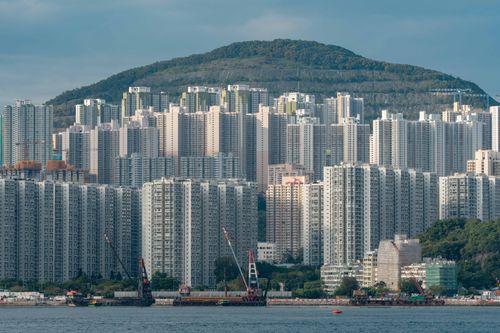 Free Majestic skyline of Hong Kong with high-rise buildings set against lush green hills. Stock Photo