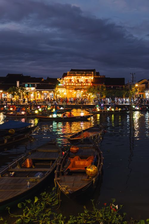 Free Colorful lantern-lit boats and bustling night market scene in Hoi An, Vietnam. Stock Photo